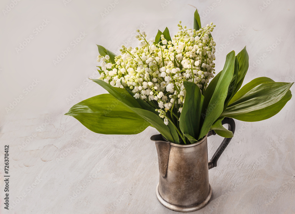 A bouquet of lilies of the valley in a coffee pot. Background for postcards, calendar.