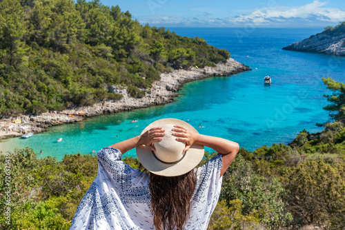 Rear view of young female wearing hat looking at amazing Zitna beach in Zavalatica, Korcula, Croatia