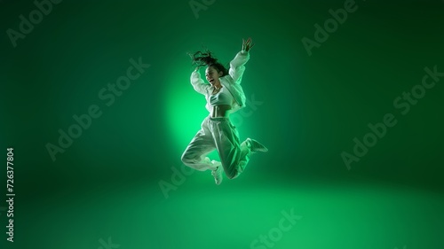 Dance in Flight, An energetic leap frozen in silhouette, embodying the spirit of a passionate hip-hop performance on a vivid saturated green neon background. Generative AI. photo