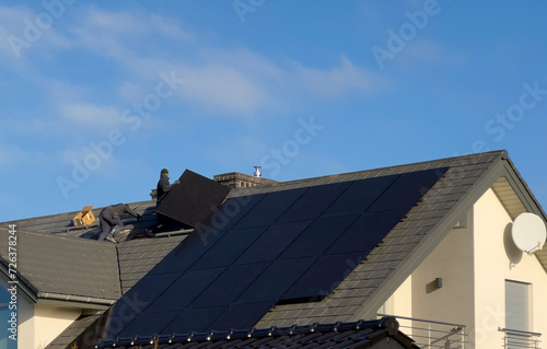 Workers installing modern solar panels on the roof of a house. Ecology and alternative energy concept.