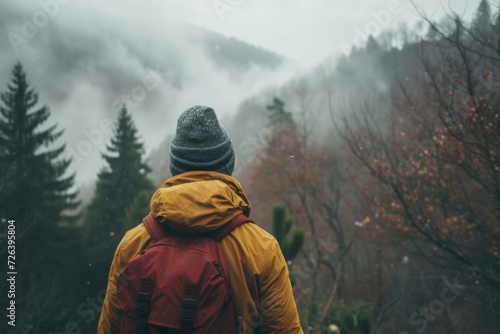 Hiker in Yellow Jacket Admiring Snowy Forest. A hiker clad in a yellow jacket gazes into a snowy, misty forest, exuding a sense of wonder and adventure. 