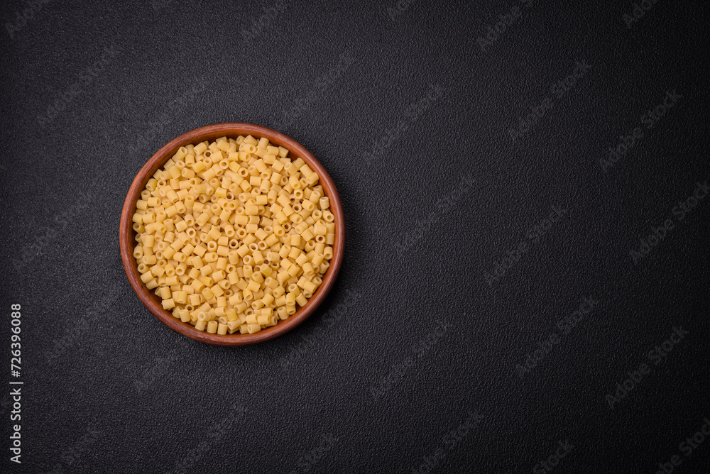 Raw ditali pasta made from durum wheat on a dark concrete background Raw ditali pasta made from durum wheat on a dark concrete background