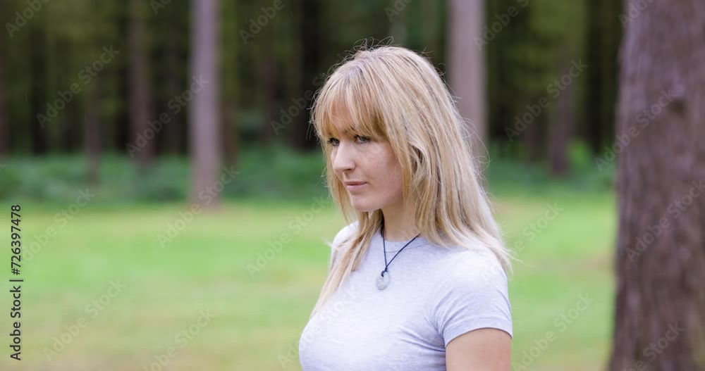 Blond woman walking in forest looking around Blond woman walking in forest looking around