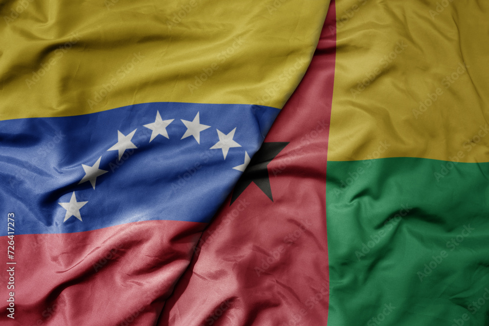 big waving national colorful flag of guinea bissau and national flag of venezuela . macro
