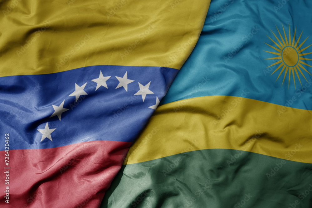 Fototapeta premium big waving national colorful flag of rwanda and national flag of venezuela . macro
