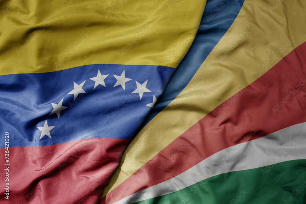 big waving national colorful flag of seychelles and national flag of venezuela . macro
