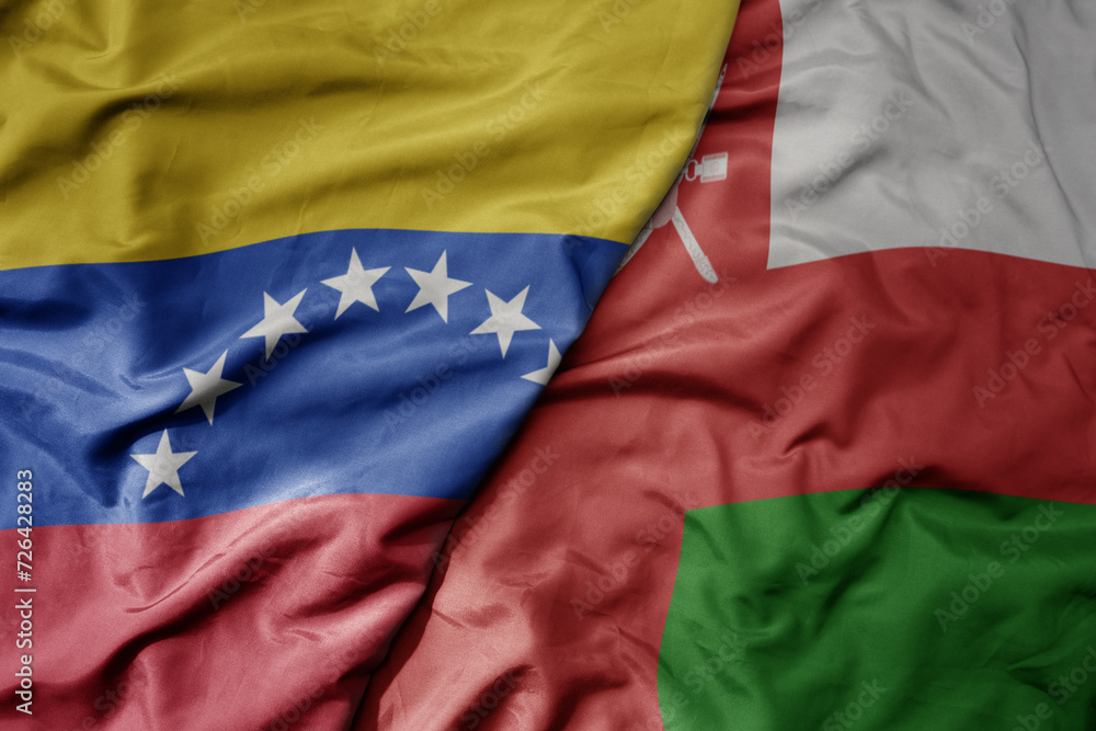 Fototapeta premium big waving national colorful flag of oman and national flag of venezuela . macro