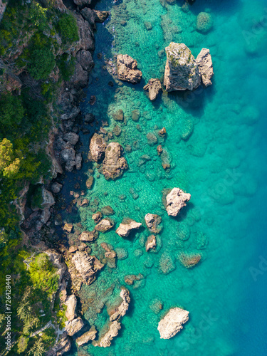 A bird's-eye view from top to bottom of the seashore. Clear azure water and rocks on the beach. Antalya, Turkey.