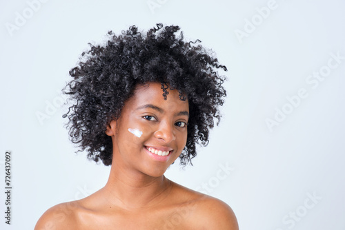 young colombian girl with afro hair in profile with cream on her face smiling on white background photo