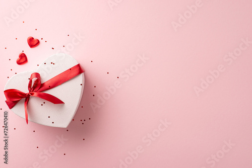 Supreme female celebration concept. Overhead perspective of snazzy heart-shaped package, trimmings, and glitter strewn on a pastel pink stage, blank area for text or advert photo