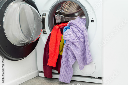 Pile of colorful clothes in a drum of a washing machine in laundry room. Washing winter clothes in the washer