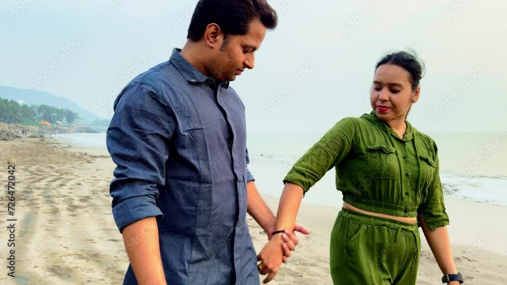 young couple holding hands walking and talking on the sandy beach young couple holding hands walking and talking on the sandy beach