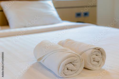 Stacked of white fluffy and cleanliness towels on bed sheet, Freshly laundered folded towels in a roll in hotel bedroom, Decoration in bedroom interior.