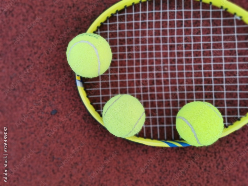 Tennis. Tennis ball and racket on a red background of tennis court with copy space. Sport and healthy lifestyle. The concept of outdoor game sports. 