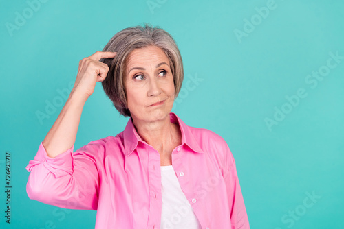 Photo of minded old business woman scratch head looking empty space contemplate analyzing plans isolated on blue color background photo