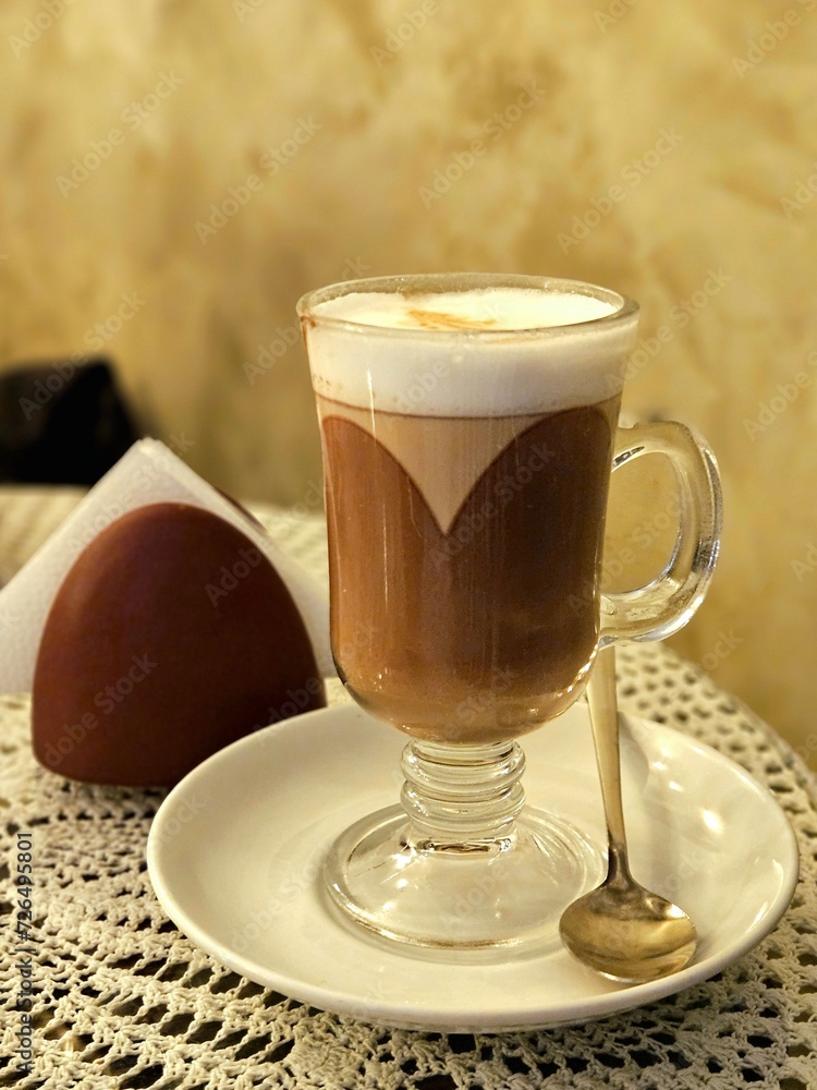 A cup of coffee (latte macchiato) standing on the table in cafe. Transparent glass with latte in a cafe A cup of coffee (latte macchiato) standing on the table in cafe. Transparent glass with latte in a cafe