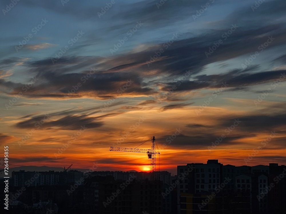 Beautiful sunset over the city. Colored clouds at sunset. Construction site at sunset. Sunset over city