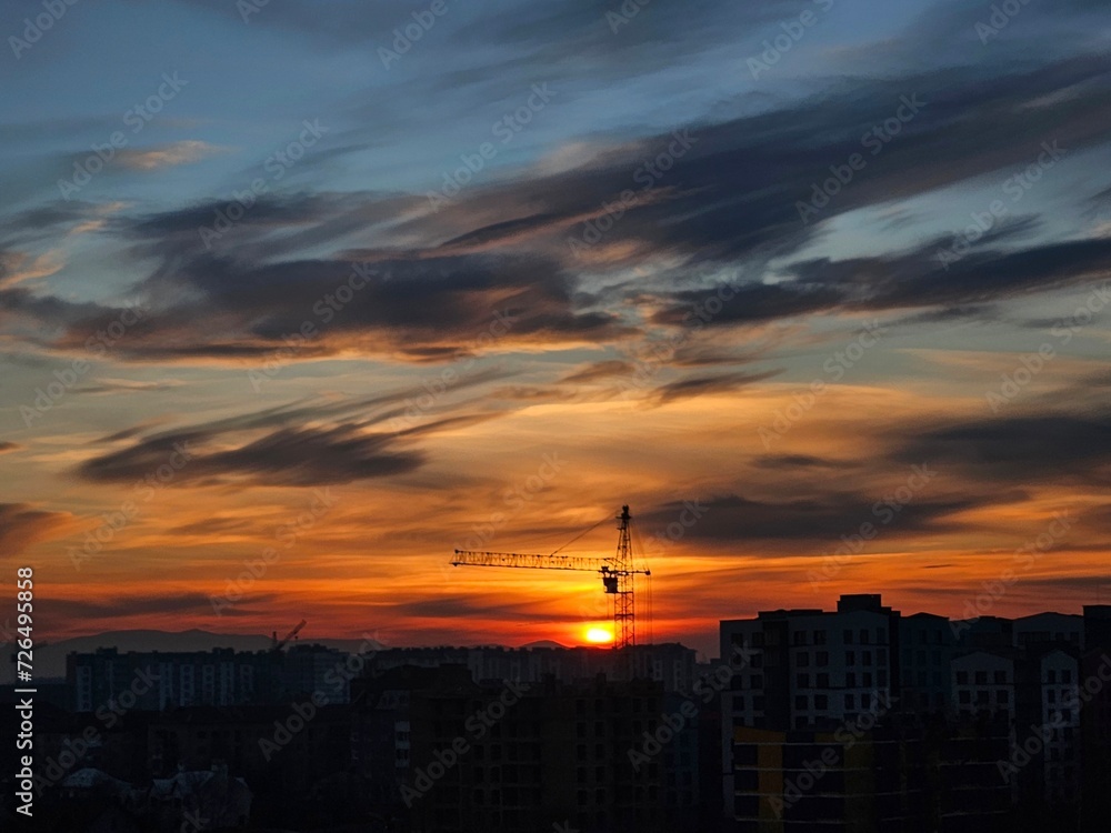 Beautiful sunset over the city. Colored clouds at sunset. Construction site at sunset. Sunset over city