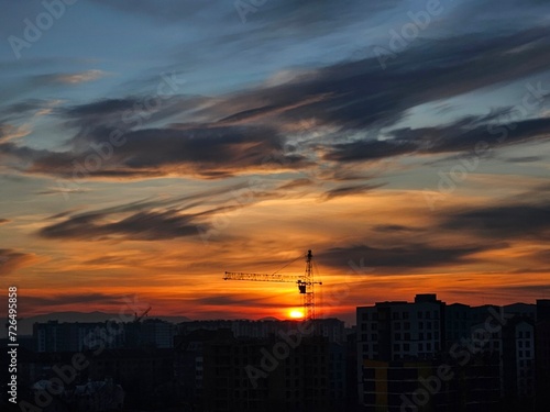 Beautiful sunset over the city. Colored clouds at sunset. Construction site at sunset. Sunset over city