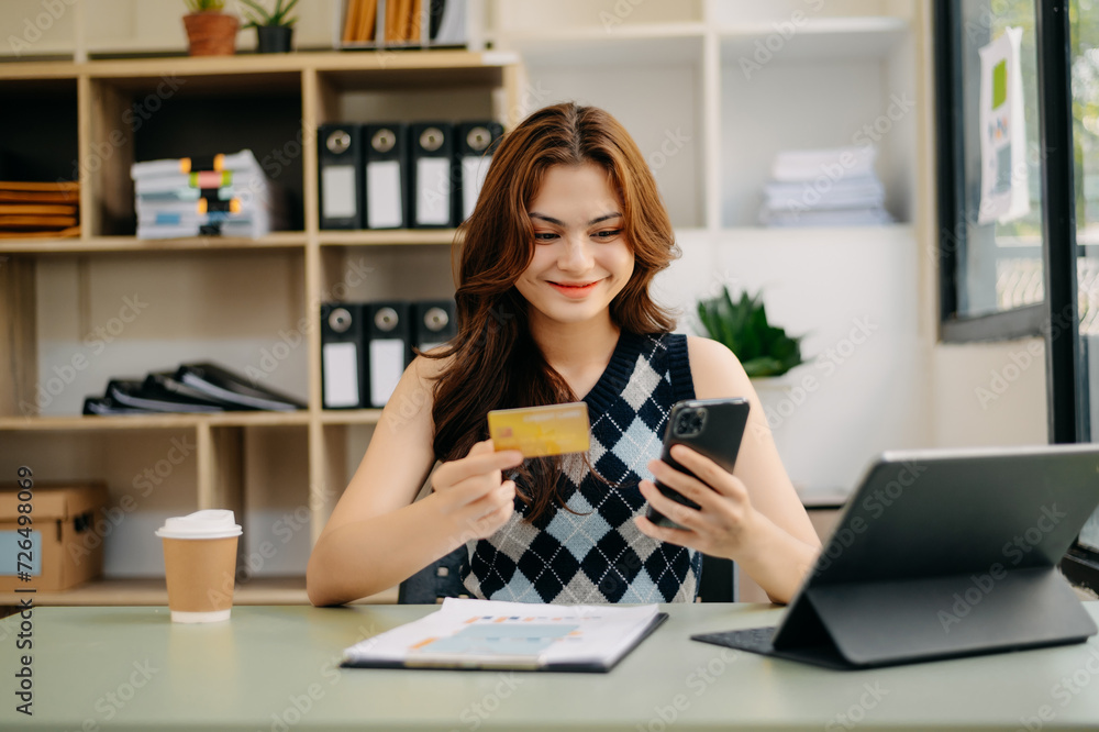 businesswoman hand using smart phone, tablet payments and holding credit card online shopping, omni channel, digital tablet docking keyboard computer at office businesswoman hand using smart phone, tablet payments and holding credit card online shopping, omni channel, digital tablet docking keyboard computer at office