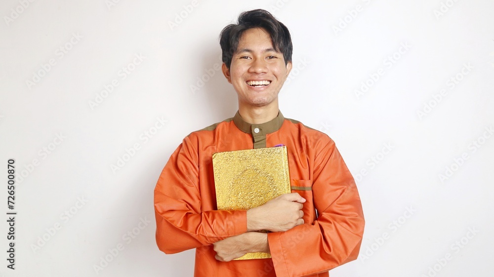Asian Muslim man smiling is holding al-quran Asian Muslim man smiling is holding al-quran