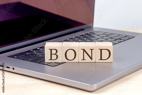 BOND word on wooden block on laptop, business concept photo