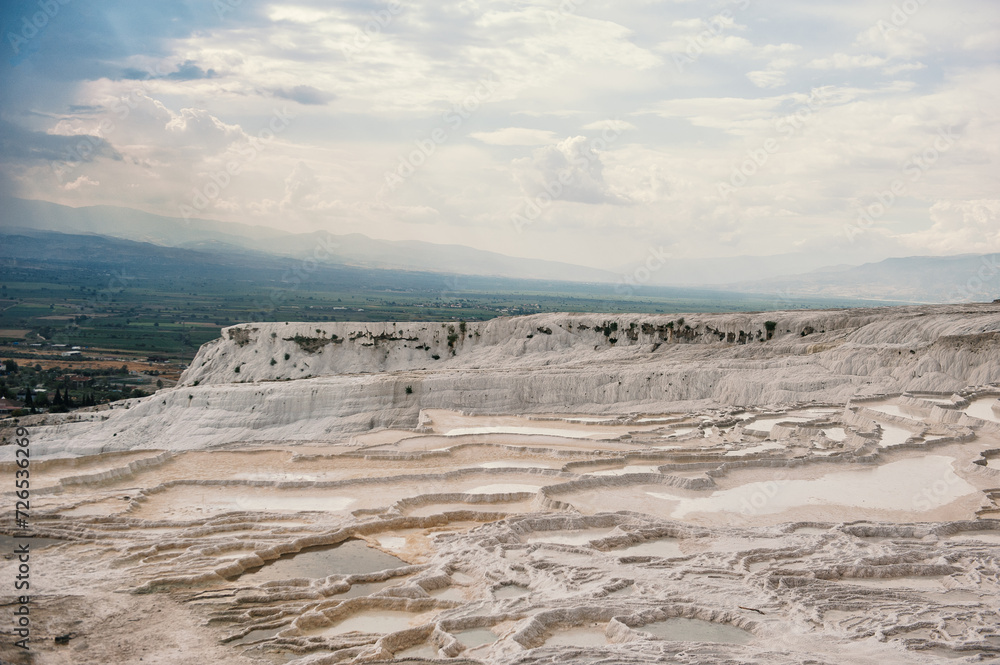 Beautiful landscape with white calcium travertine terraces and dramatic sky in Pamukkale, Turkey