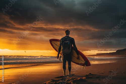Fit young surfer man with curly blond hair with surfboard goes by the ocean having fun doing extreme water sports, surfing. Travel and healthy lifestyle concept. Sports travel destination