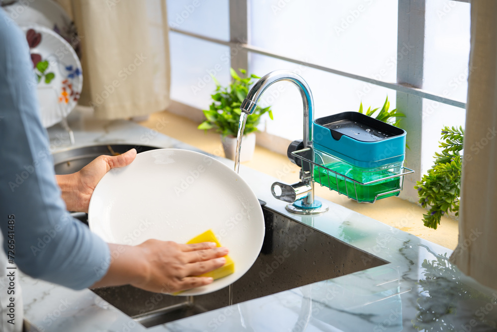 Close up shot of woman hands washing dishes or utensils at kitchen using liquid soap - concept of household domestic work and routine housework - obrazy, fototapety, plakaty 