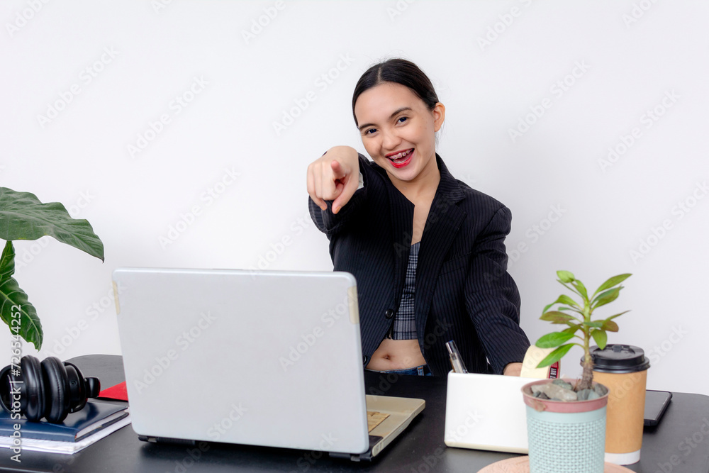 Smiling young female BPO employee pointing at the camera from her office desk, exuding confidence and friendliness. Smiling young female BPO employee pointing at the camera from her office desk, exuding confidence and friendliness.