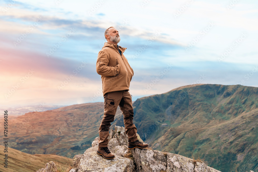 Bearded Man reaching the destination  and on the top of mountain  at sunset on autumn day  Travel  Lifestyle concept The national park Lake District in England - obrazy, fototapety, plakaty 