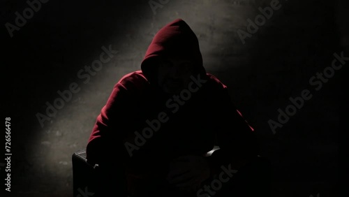 Anonymous man in a hood interview video footage, mysterious man sitting on a chair and talking. Anonymous hacker interview with no visible face footage, computer hacker conceptual background