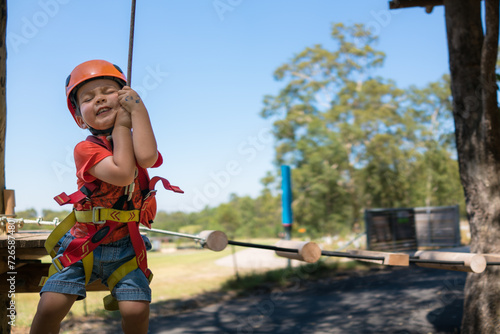 Cute 3 year old mixed race boy plays on an adventure ropes course photo