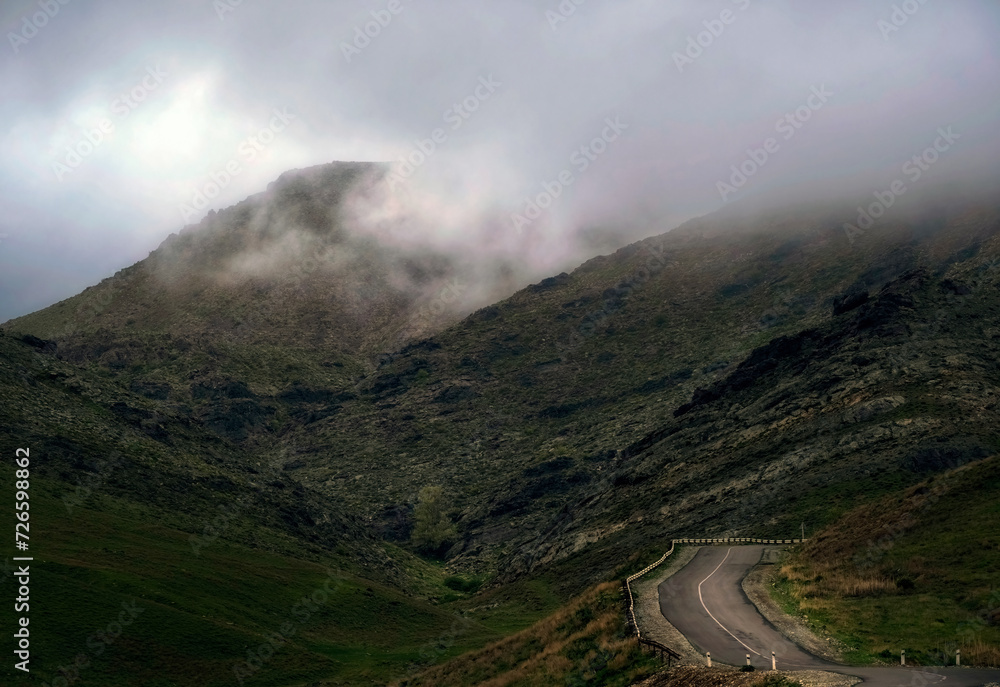 winding road in gloomy foggy rocky mountains. Dark Pass in Karatau mountains in Southern Kazakhstan