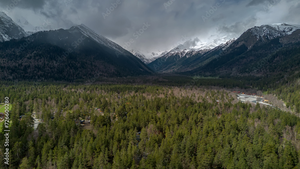 Beautiful mountain landscape. Clouds in the sky. Green grass. Snow on mountain peaks.