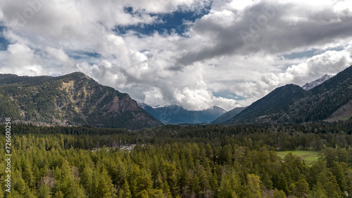 Beautiful mountain landscape. Clouds in the sky. Green grass. Snow on mountain peaks.