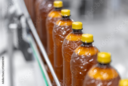 Brown plastic beer bottles moving on conveyor. Concept production line of brewery, modern food industry