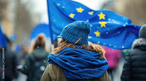 Crowd and supporters with European flags. The girl walks against the background of a blue flag. photo