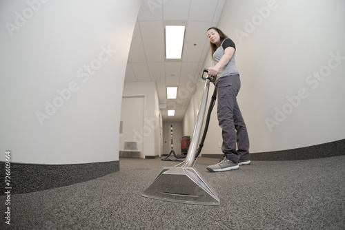 female cleaner employee removing dirt from carpet