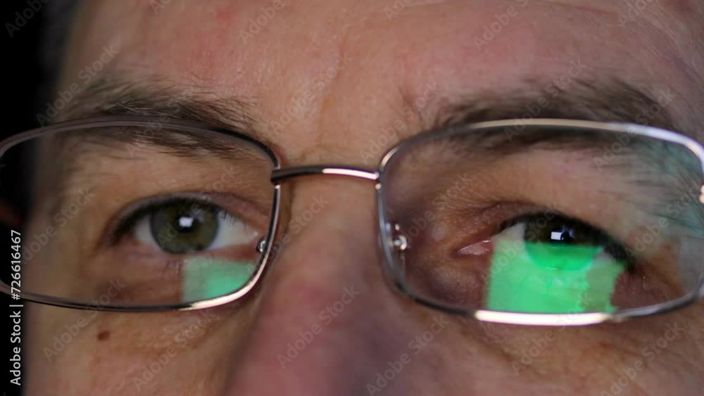 eyes of a man with eyeglasses looks at a PC screen with a computer reflection, uses the Internet, reads, works online close-up 4k video eyes of a man with eyeglasses looks at a PC screen with a computer reflection, uses the Internet, reads, works online close-up 4k video