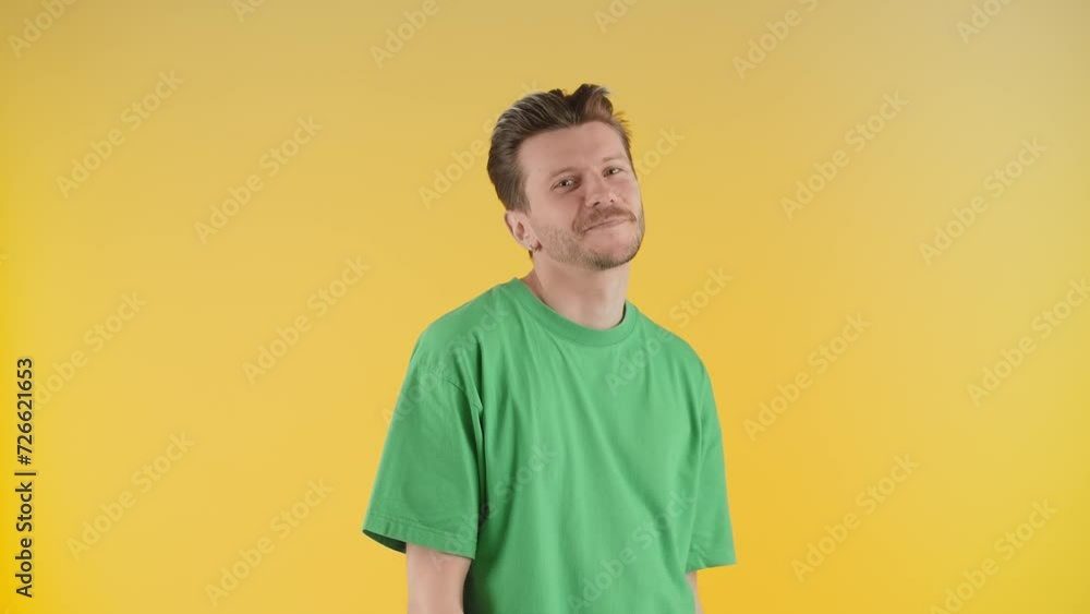 Smiling man posing on a yellow background. A young man in a green T-shirt dances in front of the camera. Smiling man posing on a yellow background. A young man in a green T-shirt dances in front of the camera.
