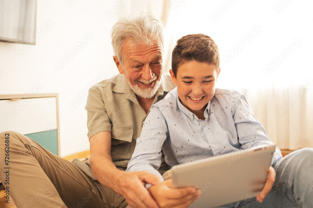Smiling boy with grandfather using tablet PC at home