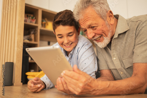 Happy grandfather and grandson using digital tablet at home