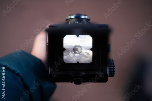 Zdjęcie aparatu analogowego. Fotograf trzyma aparat robiąc zdjęcie plaży o wschodzie słońca photo