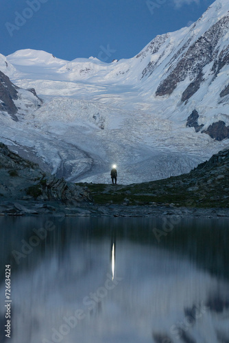 Zdjęcie turysty który maszeruje po zmroku na tle lodowca