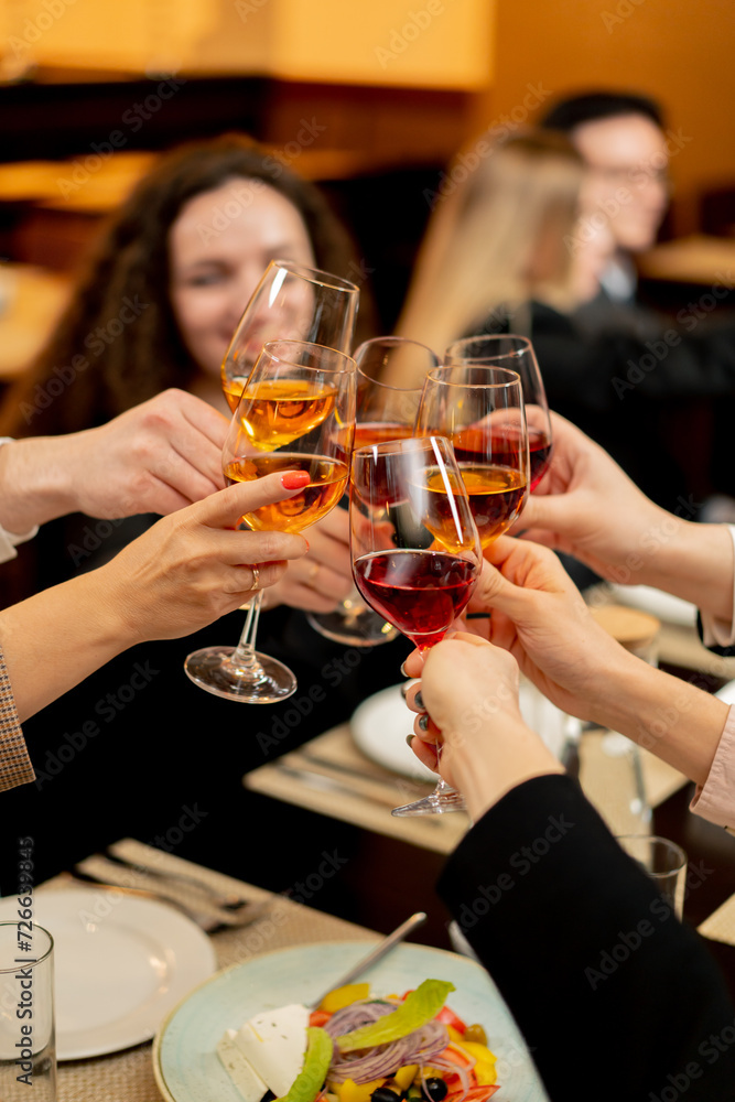 colleagues at work are sitting in a restaurant, celebrating the conclusion of a new agreement toasts with glasses of wine close-up