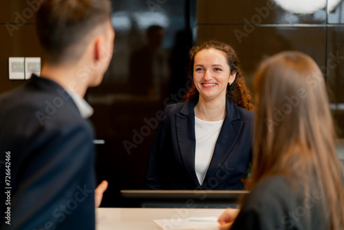 The receptionist at the counter meets guests with luggage in the hotel business travel hospitality photo