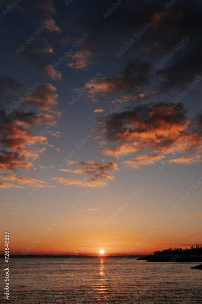 silhouette of the coast against the backdrop of the setting sun and clouds in the sky, the sun's path is reflected on the sea water silhouette of the coast against the backdrop of the setting sun and clouds in the sky, the sun's path is reflected on the sea water