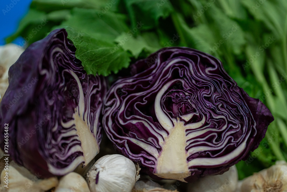 Obraz premium red cabbage cut in two on green vegetables background