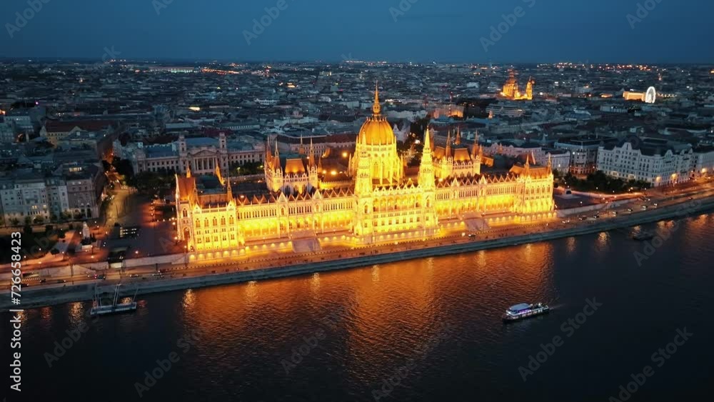 Residence of Hungarian Parliament, Budapest Aerial view national building symbol night city lights against backdrop sunset evening on sunny day in summer view from other bank of Danube River. Travel Residence of Hungarian Parliament, Budapest Aerial view national building symbol night city lights against backdrop sunset evening on sunny day in summer view from other bank of Danube River. Travel